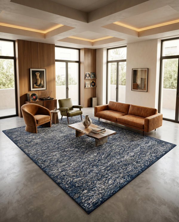 Navy blue flecked rug on a concrete floor with a tan leather sofa, olive armchair, walnut console and record player.