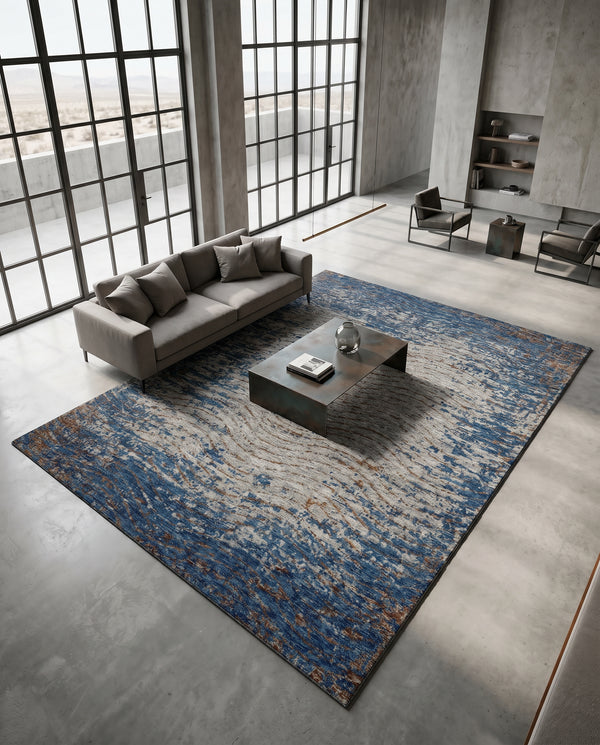 Blue and rust rug on a polished concrete floor in a loft living room with a grey sofa and low metal coffee table.