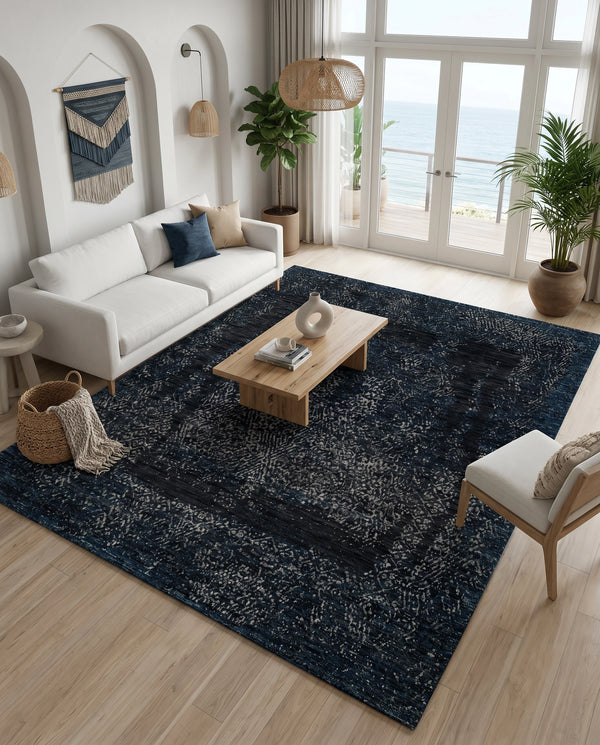 Black and blue rug on light wood flooring with a white sofa, oak coffee table and ocean view doors behind.