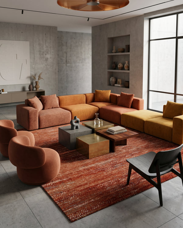 Rust and ivory rug on a concrete floor with terracotta and ochre modular sofas, brass and walnut side tables.