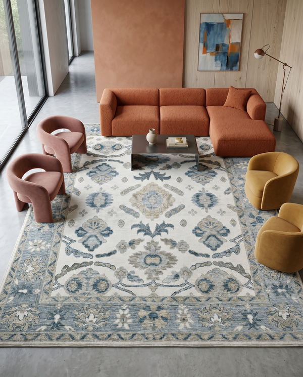 Blue and ivory floral rug on a concrete floor with a rust boucle sectional, pink armchairs and mustard swivel chairs.